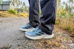 Man wearing blue trainers with a white edge on a dirt track.