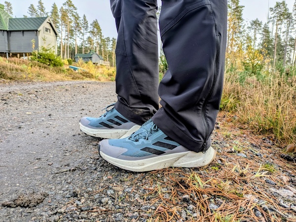 Man wearing blue trainers with a white edge on a dirt track.